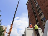 crane loading Telecom shelters on a building